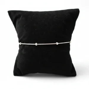 srebrna minimalisticka narukvica sa kuglicama na crnom postolju bela pozadina