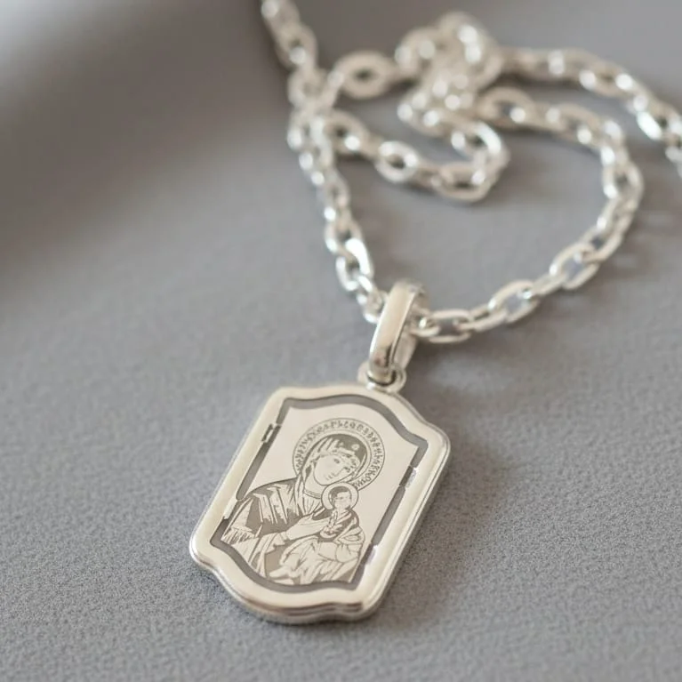 Srebrni pravougaoni privezak sa graviranim likom Bogorodice i malog Isusa na srebrnom lancu.