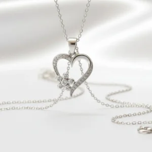 Srebrni privezak u obliku srca sa malim cvetom ukrašenim cirkonima na srebrnom lancu.