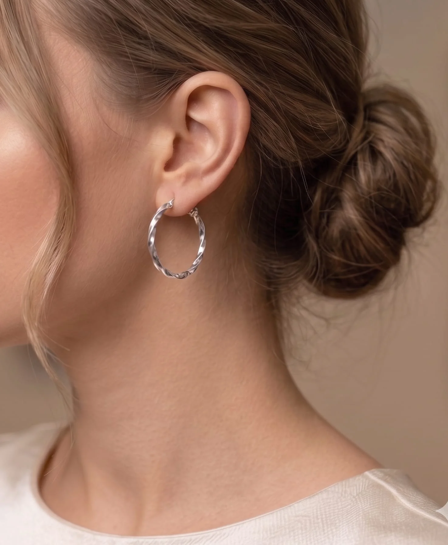Srebrne minđuše alke sa spiralno upletenim dizajnom i jasno vidljivim žigom 925 na kopči na modelu.